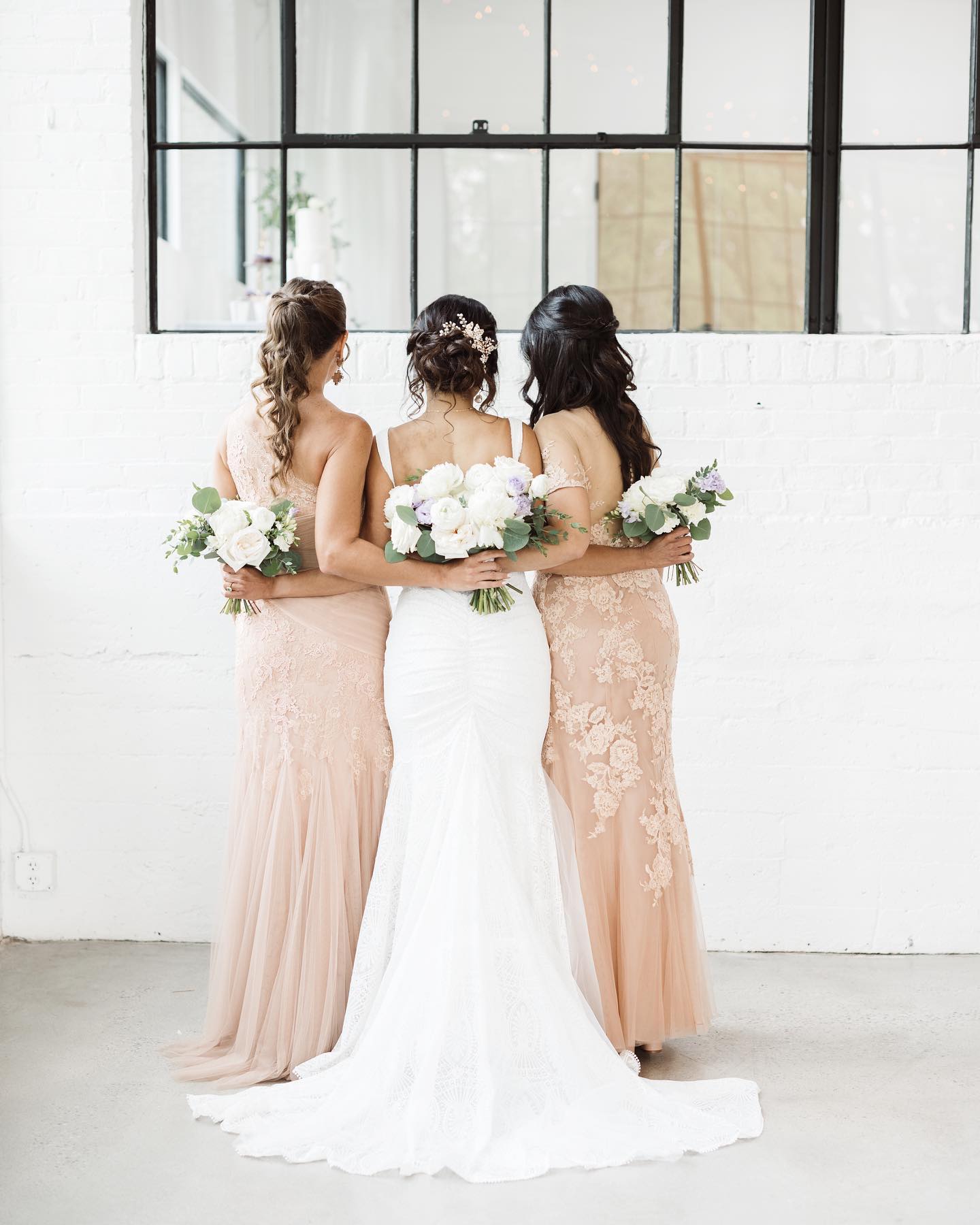 Bride and bridesmaids in finished wedding dresses holding their bouquets