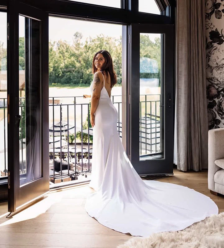 Bride in a white gown looking back from the balcony doorway