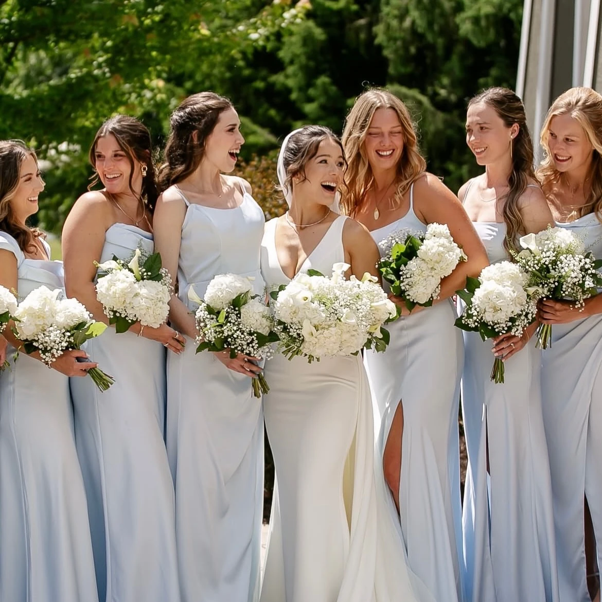 Bride and bridesmaids with white bouquets in a garden
