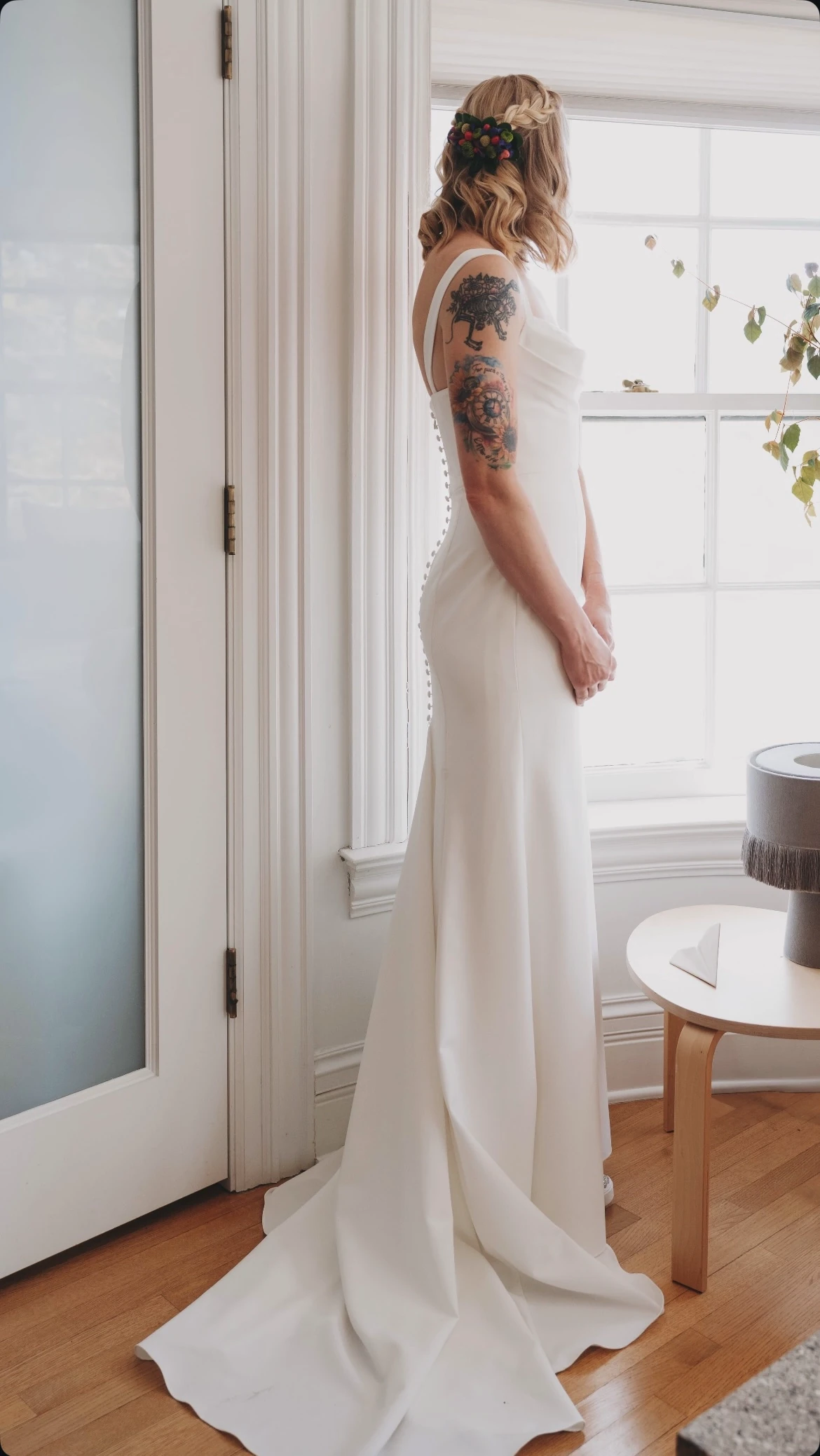 Bride in a white gown beside a bright window
